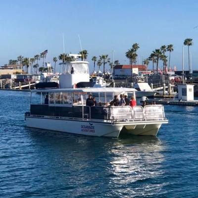 a small boat in a large body of water with Balboa Island Ferry in the background